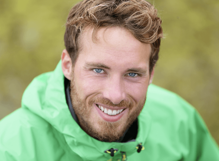 Confident man smiling after replacing knocked-out front tooth with a dental implant
