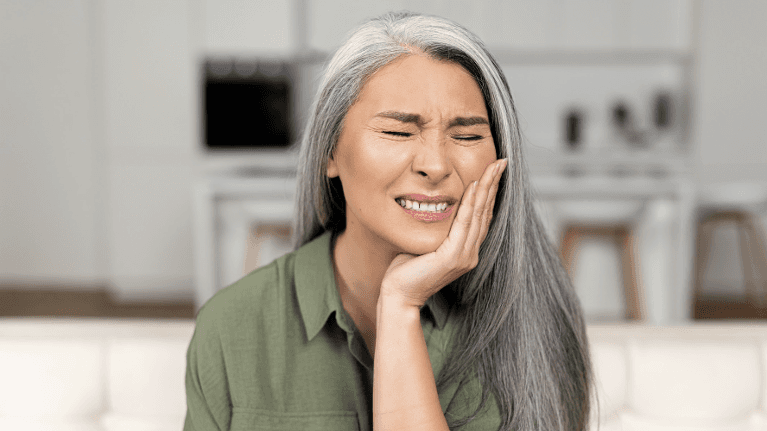 woman in pain while holding her left cheek
