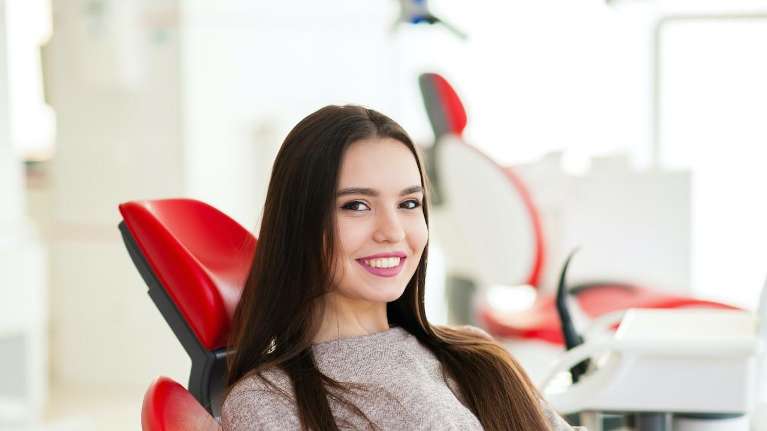 woman sitting in a red dental chair
