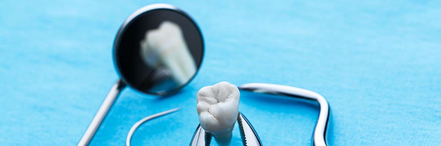 Dental tools and a toothbrush on a blue surface, emphasizing post-extraction care
